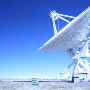 A large satellite dish observatory against a clear blue sky in a desert landscape, capturing signals.