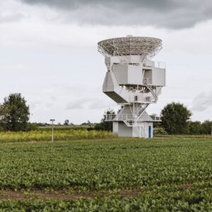 A large satellite antenna stands prominently in a lush field in Riedstadt, Germany.