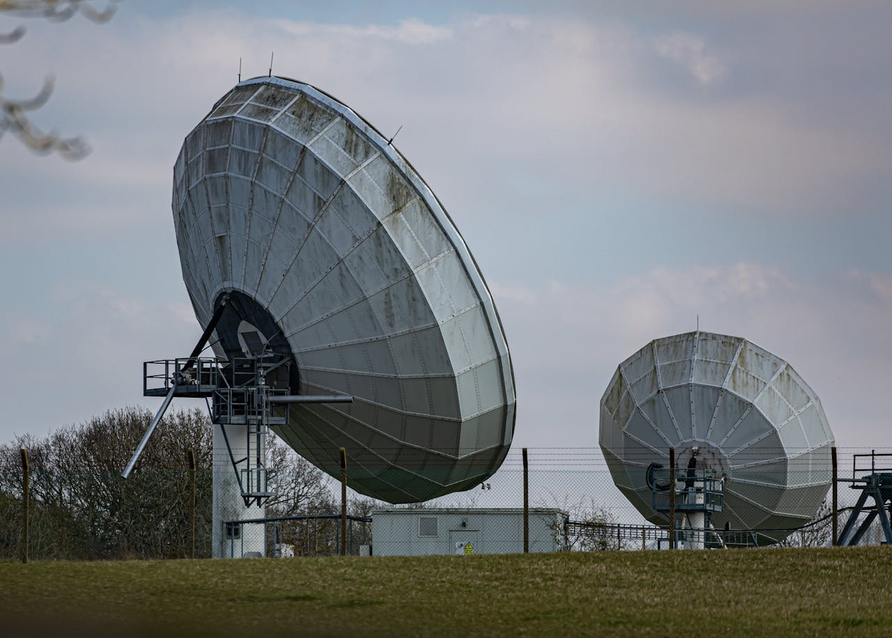 Two large radio telescopes in an outdoor setting, showcasing astronomy and science technology.